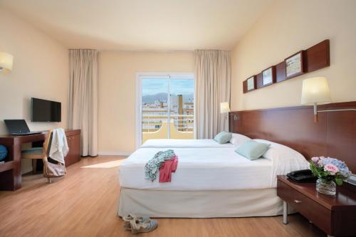 ein Hotelzimmer mit einem großen Bett und einem Fenster in der Unterkunft Prestige Victoria in Roses