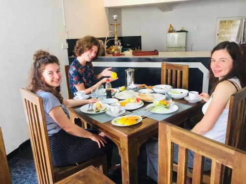 three women sitting around a table eating food at The Lake Round Guest House in Kandy