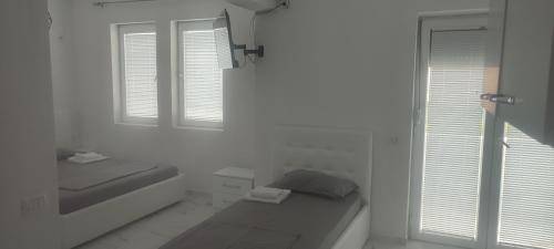 a white room with a bed and two windows at Golem Apartment in Golem