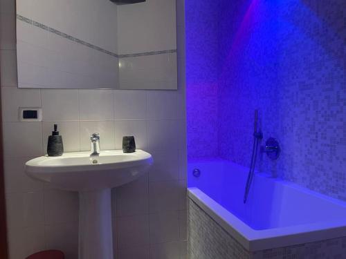 uma casa de banho com um lavatório e uma banheira com luz roxa em Casa in piazzetta em Rivergaro