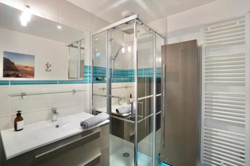 uma casa de banho com uma cabina de duche em vidro e um lavatório. em Les sables blancs*50m de la mer* em Concarneau