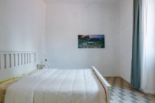 Lucca Historic & Cozy Central Apartment! في لوكّا: سرير أبيض في غرفة نوم مع صورة على الحائط