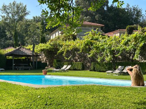 une femme debout à côté d'une piscine dans une cour dans l'établissement Villa Margaridi, à Guimarães