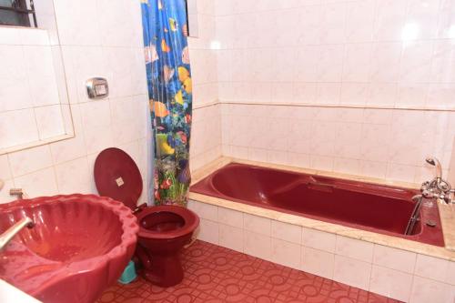 y baño con aseo rojo y bañera. en Rosa’s Guest House, en Siroda