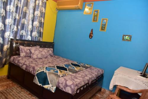 1 dormitorio con 1 cama con pared azul en Rosa’s Guest House, en Siroda