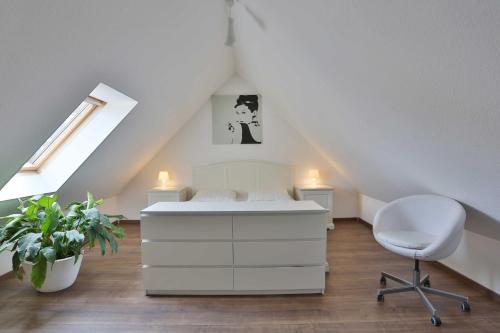 ein Schlafzimmer mit einem weißen Bett und einem Stuhl in der Unterkunft Hochwertige Ferienwohnung direkt am Wasser mit Balkon in Greifswald