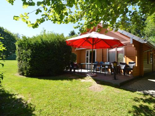 een patio met een tafel en een parasol op een huis bij Comfortable Chalet in Ovifat near Ski Lift in Waimes