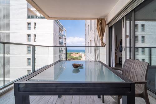 uma mesa de vidro numa varanda com vista para o oceano em Achziv Beach Haven 3BR Apartment by Sea N' Rent em Nahariya