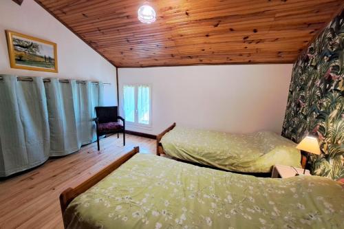 1 dormitorio con 2 camas y techo de madera en Les Glycines, en Saint-Pierre-de-Buzet