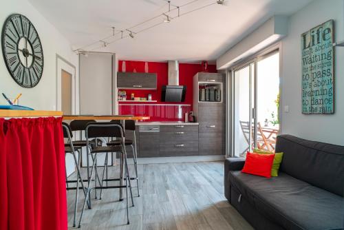 - un salon et une cuisine avec des murs rouges et un canapé dans l'établissement Les Cormorans - Appt en rdc avec jardin, à Bénodet