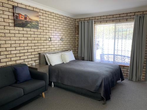 1 dormitorio con cama, sofá y ventana en Cowra Crest Motel, en Cowra