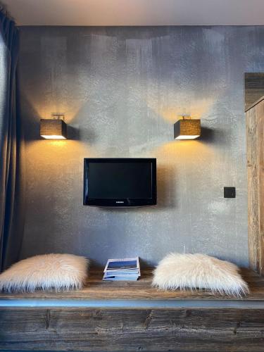 - deux oreillers blancs assis sur une étagère et une télévision dans l'établissement IMMODREAMS - Le Flocon, à Avoriaz