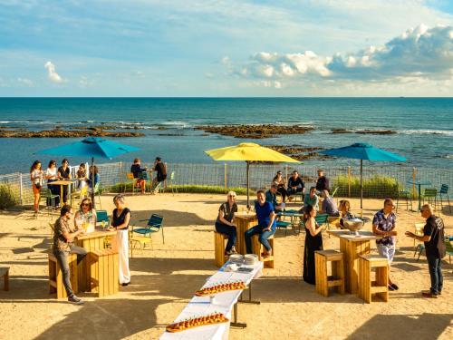 a group of people sitting at tables on the beach at La Villa Saint Jean in Les Sables-dʼOlonne