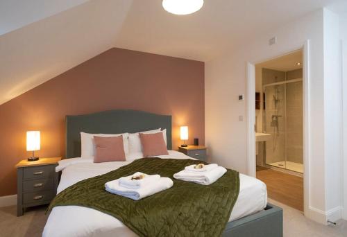 a bedroom with a large bed with two towels on it at Comfortable townhouse in Tetbury, parking & garden in Tetbury