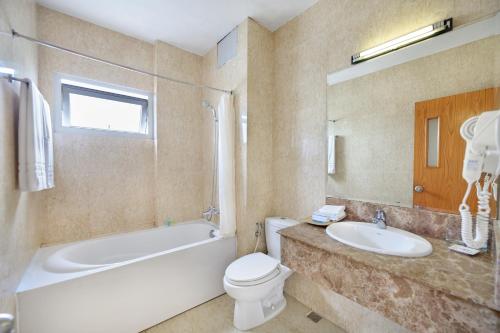 a bathroom with a sink and a toilet and a bath tub at Danang Petro Hotel in Da Nang