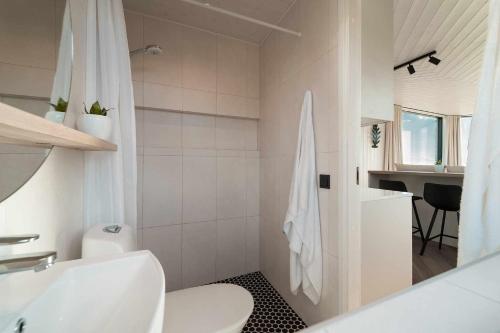 a white bathroom with a toilet and a sink at Exclusive off-grid tiny home at the beach - Kenshó 