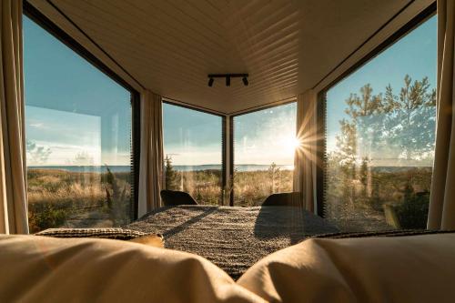 a bedroom with a bed and large windows at Exclusive off-grid tiny home at the beach - Kenshó 