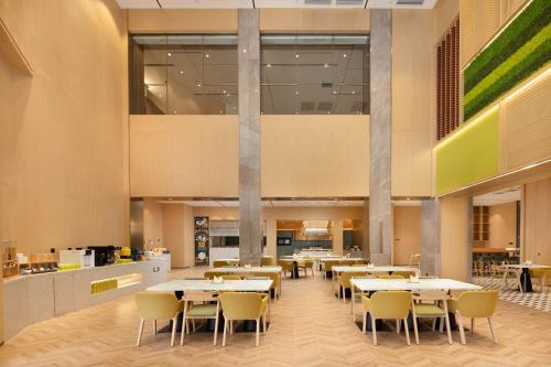 uma área de jantar com mesas e cadeiras numa cafetaria em Home2 Suites by Hilton Beijing West Station em Pequim