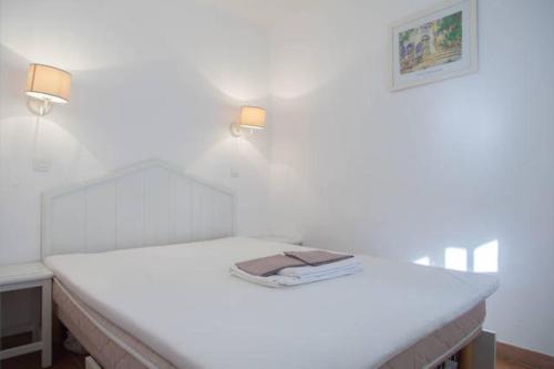 - un lit blanc avec deux lumières au-dessus dans l'établissement Fantastisk feriebolig med basseng og kort vei til havet, à Saint-Raphaël