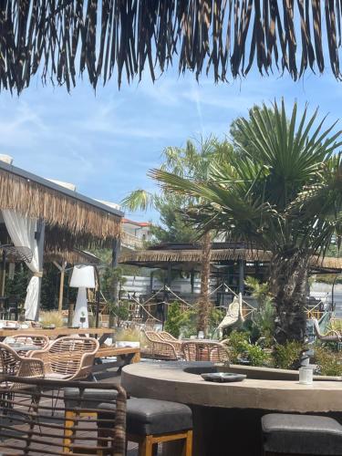 a patio with tables and chairs and palm trees at Ellie's Eco Private Glamping and Spa in Nea Kalikratia