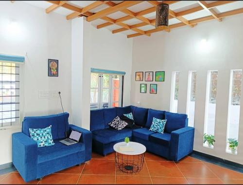 una sala de estar con sofás azules y una mesa. en Nostalgia Homestay, en Vythiri