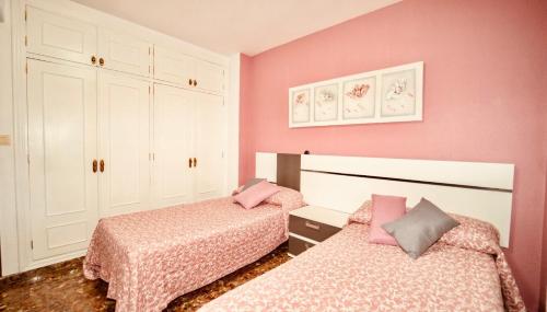 two beds in a pink bedroom with pink walls at Apartamento Jose Enrique in Granada