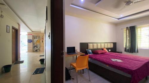 a bedroom with a bed and a desk and a chair at C Suites - Richfield in Bangalore