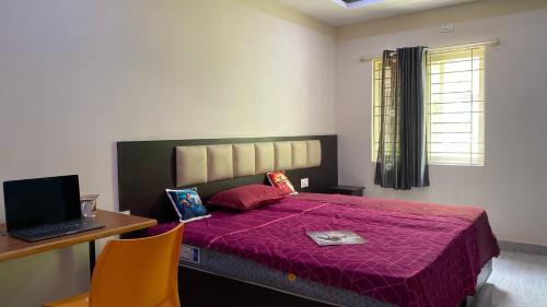 a bedroom with a bed and a desk with a laptop at C Suites - Richfield in Bangalore