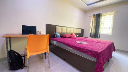 a bedroom with a bed and a desk with a laptop at C Suites - Richfield in Bangalore