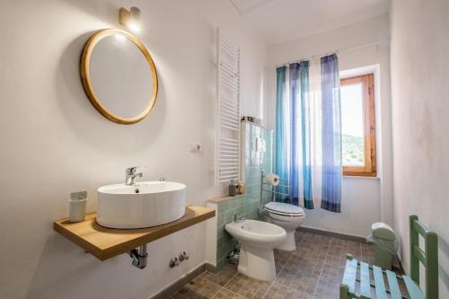 a bathroom with a sink and a toilet and a mirror at La sosta del pellegrino in Sorano