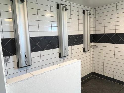 a bathroom with three mirrors on a tiled wall at Hirtshals Idrætscenter - Vandrehjem - Hostel in Hirtshals