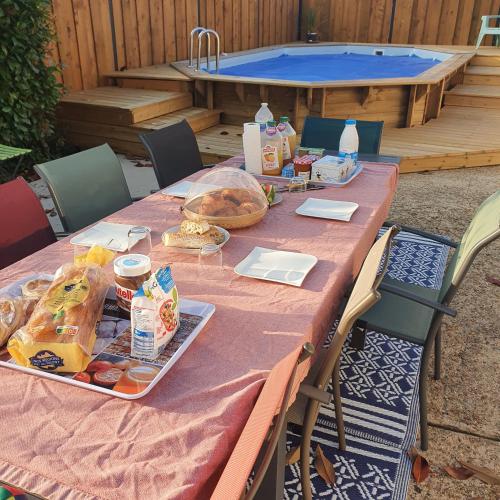 une table de pique-nique avec de la nourriture dessus devant une piscine dans l'établissement Maison familliale à la campagne à 15 min du mans, à Roézé-sur-Sarthe