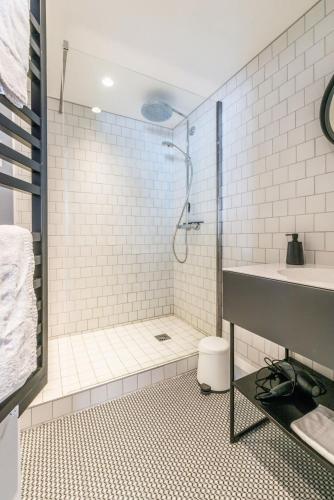une salle de bain carrelée blanche avec une douche et un lavabo dans l'établissement IMMODREAMS - Le Moutain Loft, à Morzine