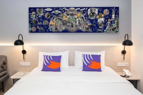 FOX Lite Hotel Samarinda في ساماريندا: سرير مع وسادتين ولوحة فوقه