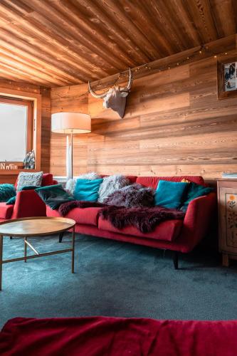 - un canapé rouge dans une chambre dotée d'un mur en bois dans l'établissement IMMODREAMS - Le Lodge, à Avoriaz