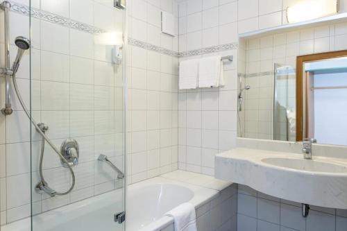 a bathroom with a shower and a sink and a tub at Hotel Unser Unterberg in Maria Alm am Steinernen Meer