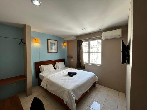 una camera da letto con un letto con un cappello sopra di Hotel Harbour Stay a Malacca
