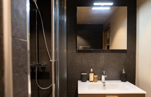 a bathroom with a sink and a shower with a mirror at IMMODREAMS - La Cabane in Morzine
