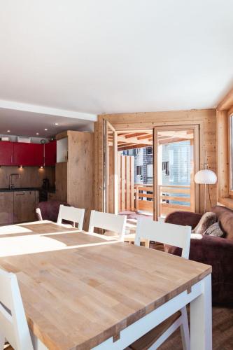 une salle à manger avec une grande table en bois et des chaises blanches dans l'établissement IMMODREAMS - Le Proclou, à Morzine