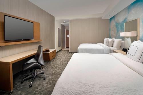 a hotel room with two beds and a desk and a tv at Courtyard by Marriott Nashville SE/Murfreesboro in Murfreesboro