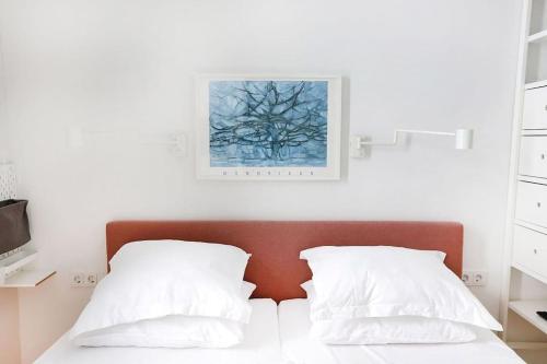 Una cama con dos almohadas blancas y un cuadro en la pared. en Wilhelminalaan 43a, Mondriaan, en Vrouwenpolder