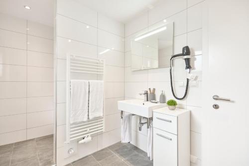 y baño blanco con lavabo y ducha. en Pension - Ferienwohnungen Zollner, en Villach