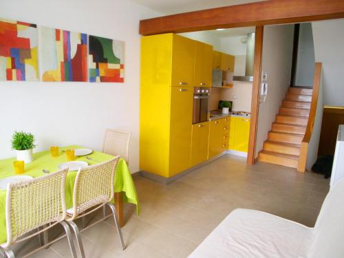 a room with a table and a kitchen with yellow cabinets at Appartamento Zipser II in Grado