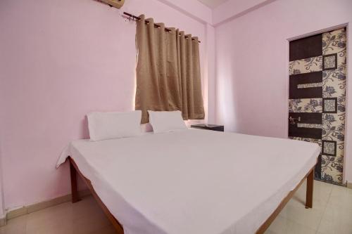 a white bed in a room with a window at Super OYO Hotel Elite Inn in Korādih
