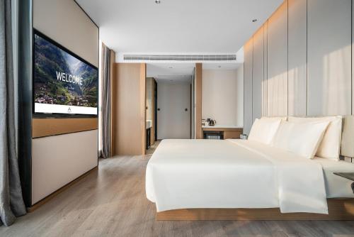 a bedroom with a white bed and a flat screen tv at Atour Hotel Chongqing Liangjiang District Jinke Center in Chongqing