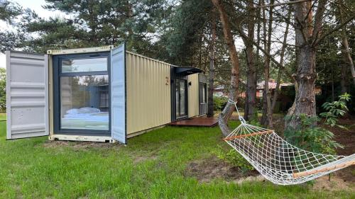 a tiny house with a hammock in a yard at Arche Siedlisko Piłka Boisko in Piłka