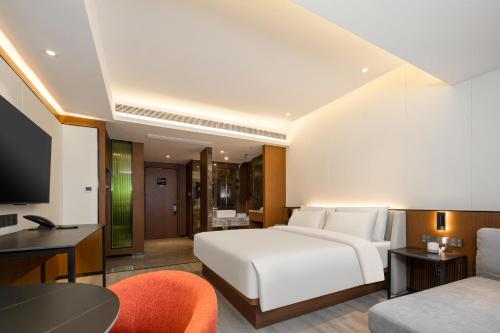 1 dormitorio con cama blanca, sofá y mesa en Atour X Hotel Taizhou Jiangyan, en Taizhou