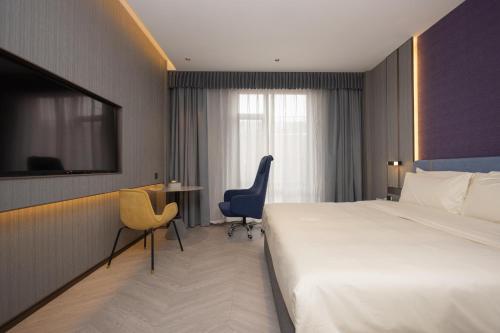 a hotel room with a bed and a desk and chair at Atour X Hotel Shanghai Hongqiao National Exhibition Qibao Old Street in Shanghai