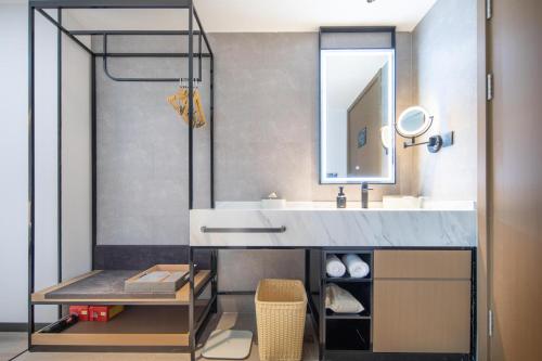 ein Bad mit einem Waschbecken und einem Spiegel in der Unterkunft Atour Hotel Suqian Industrial Park Wuyue Plaza in Suqian