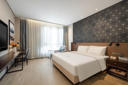 een hotelkamer met een groot wit bed en een bureau bij Atour X Hotel Suzhou Xiangcheng Vigorous Island Subway Station in Suzhou
